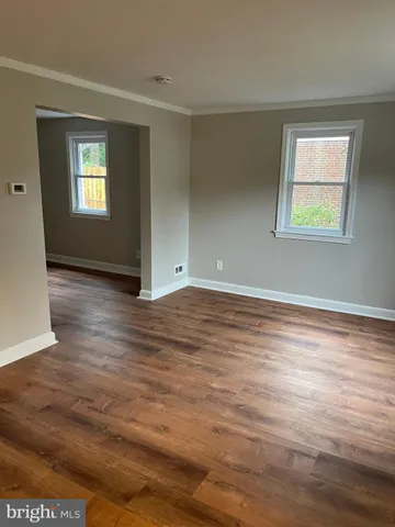a view of an empty room with window and wooden floor