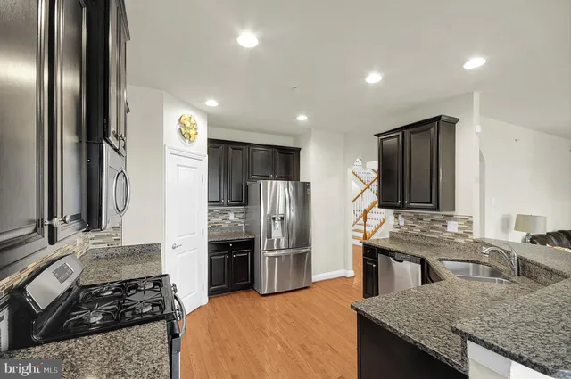 a kitchen with kitchen island granite countertop stainless steel appliances a stove a sink and a refrigerator