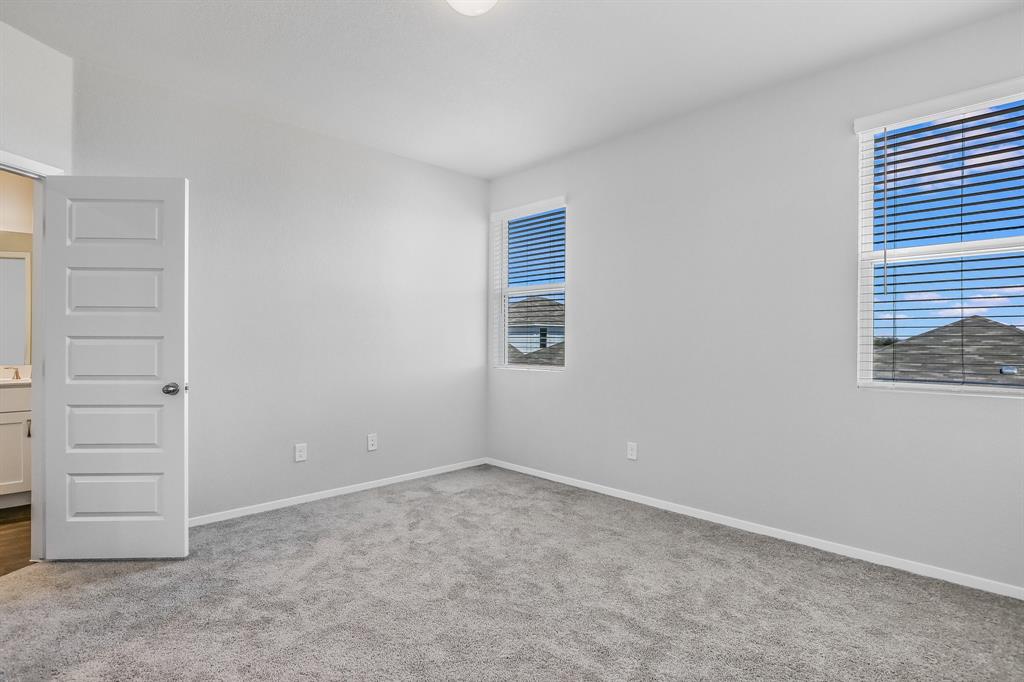 2808 Totley Road Manor, TX 78653 - Photo 10 of 21 Carpeted interior room featuring two windows with blinds, a five-panel interior door, and a built-in light fixture