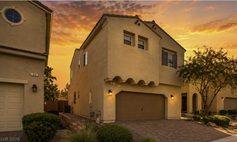 32 Lily Grove Road Las Vegas, NV 89148 - Photo 2 of 53 Golden hour illuminates this stucco residence with an attached garage and a charming front entryway.