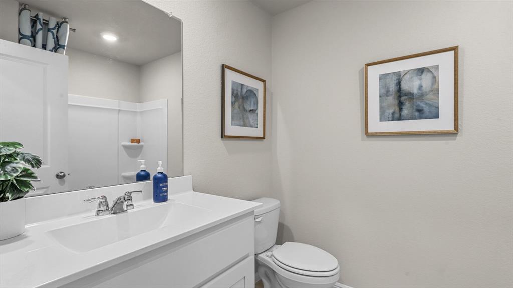 557 Marsh Street Cleburne, TX 76033 - Photo 27 of 40 a bathroom with a toilet a sink and mirror