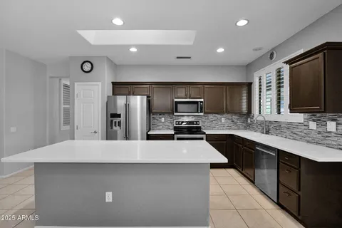 a large kitchen with a large counter top stainless steel appliances and cabinets