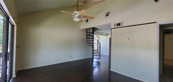 en empty room with wooden floor and fan