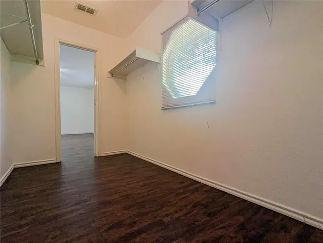 an empty room with wooden floor and mirror