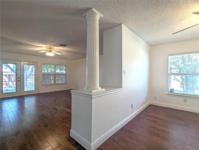 an empty room with wooden floor and windows