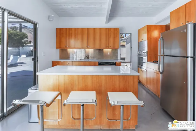 a kitchen with stainless steel appliances wooden floor and chairs