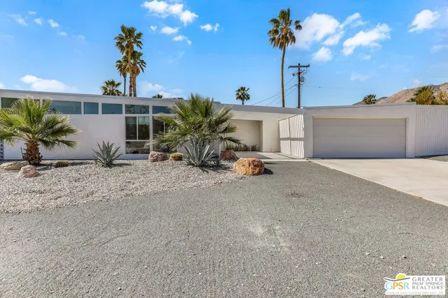 a view of a house with a yard and potted plants