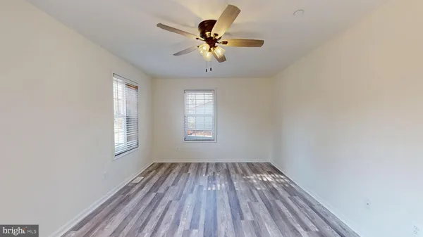 a view of a hallway with wooden floor and a bathroom