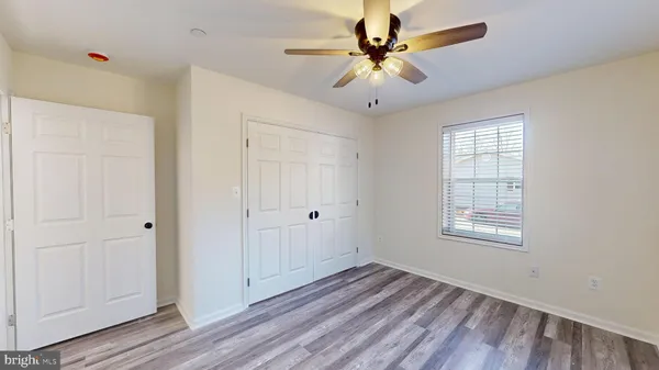 a view of a room with wooden floor and a ceiling fan