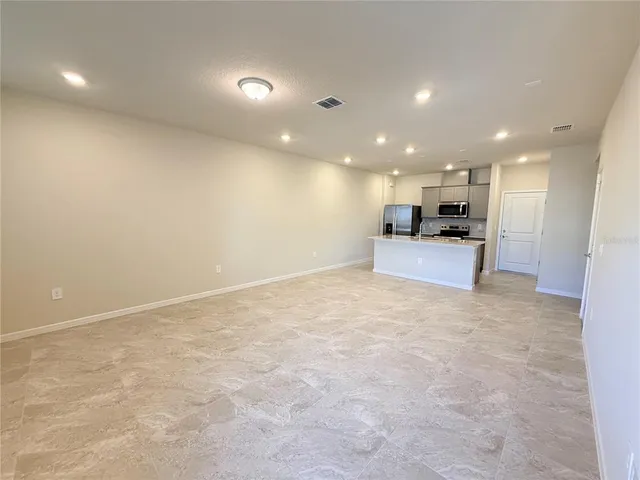 an empty room with kitchen view and stainless steel appliances