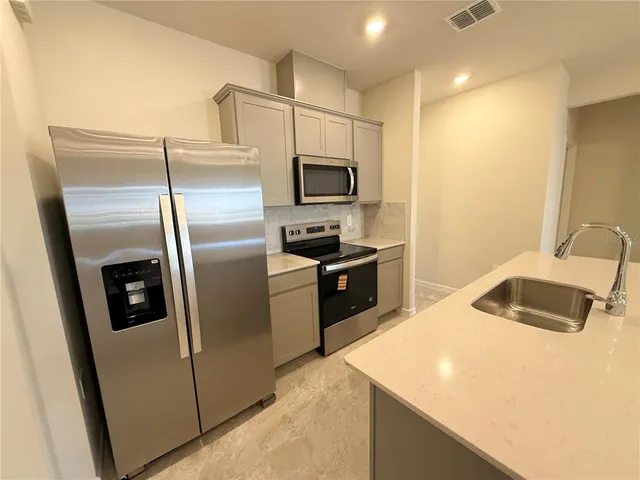 a kitchen with stainless steel appliances kitchen island a refrigerator sink and microwave