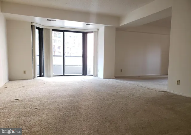 an empty room with windows and chandelier fan