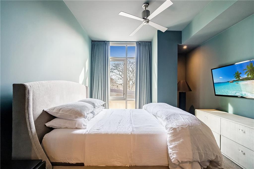 905 Juniper Street Northeast, Unit 405 Atlanta, GA 30309 - Photo 12 of 34 a bedroom with a bed and a flat screen tv