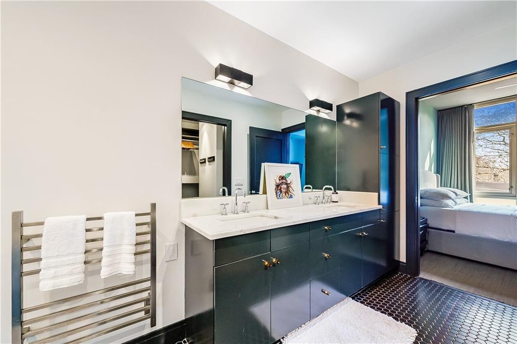 905 Juniper Street Northeast, Unit 405 Atlanta, GA 30309 - Photo 16 of 34 a en suite bathroom with a double vanity sink a mirror and a bathtub