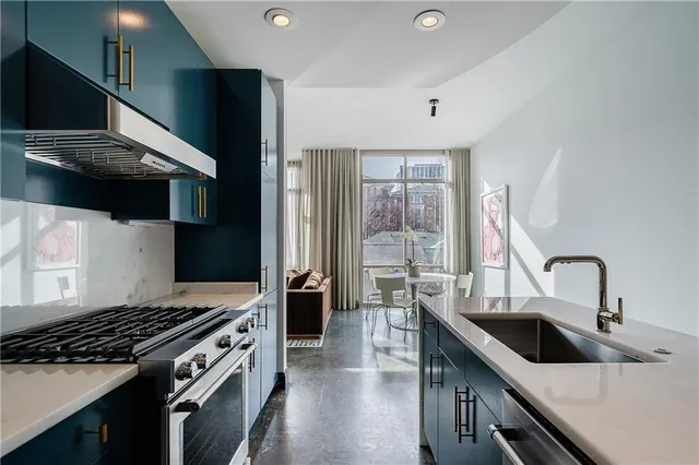 a kitchen with stainless steel appliances a sink dishwasher a stove and a refrigerator with wooden floor