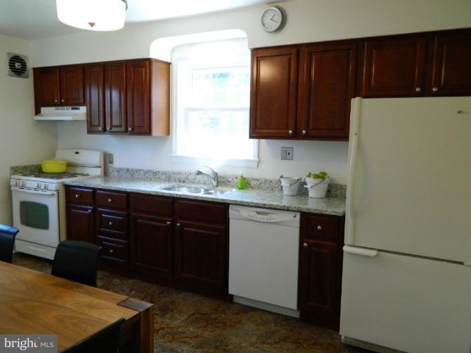 729 Charing Cross Road Baltimore, MD 21229 - Photo 9 of 26 a kitchen with granite countertop wooden cabinets and white appliances