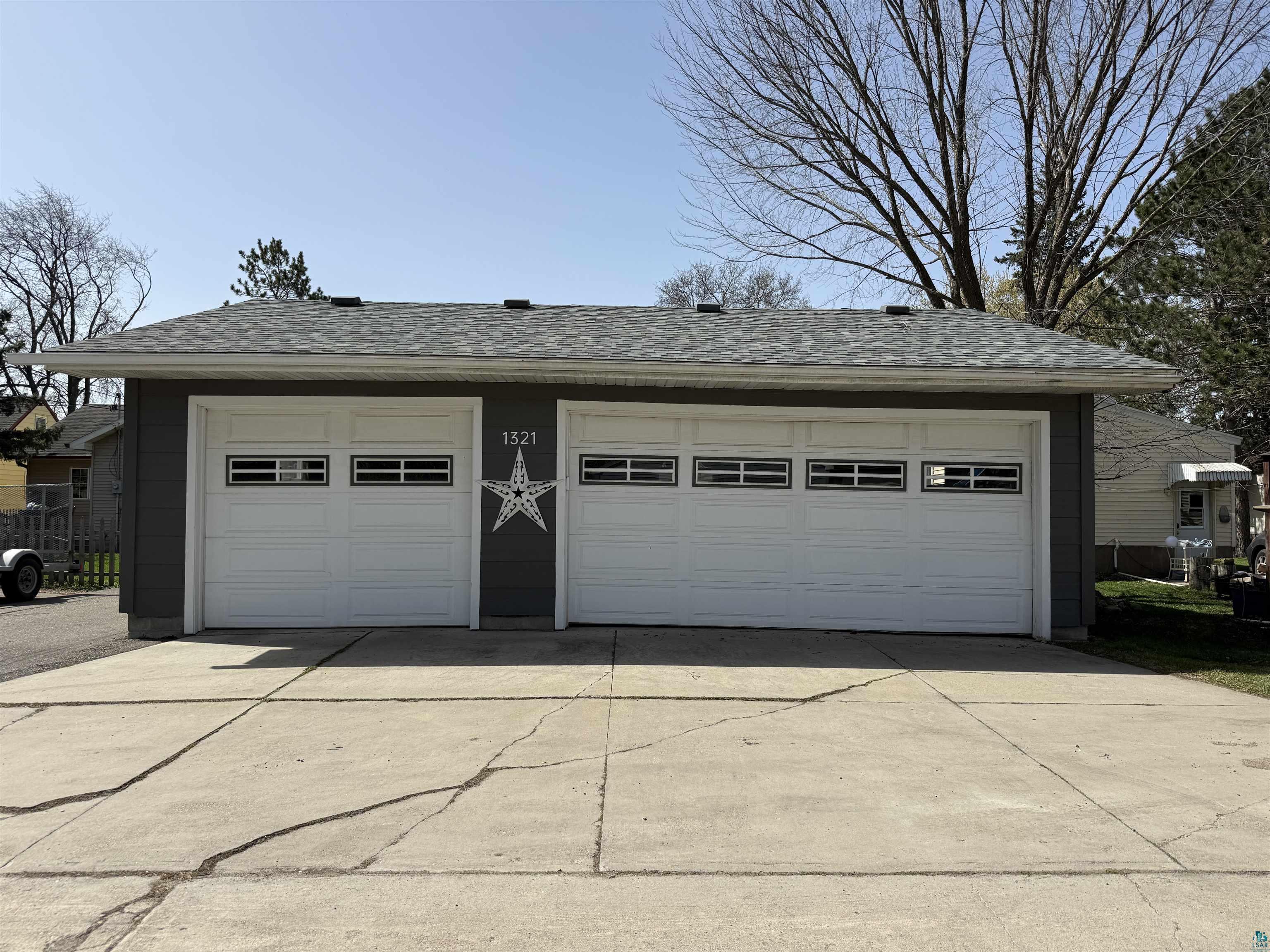 1321 South 13th Street Virginia, MN 55792 - Photo 32 of 33 Two-car garage featuring white panel doors with horizontal window inserts, dark gray siding, and a shingled roof