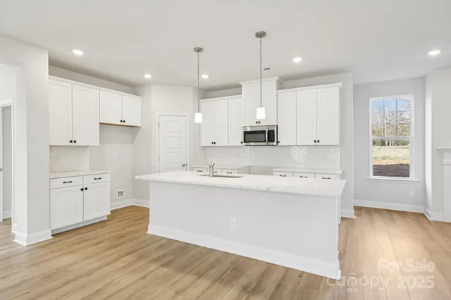a large kitchen with stainless steel appliances kitchen island a large counter top and a wooden floors