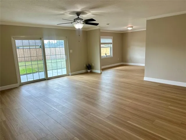 a view of an empty room with window and wooden floor