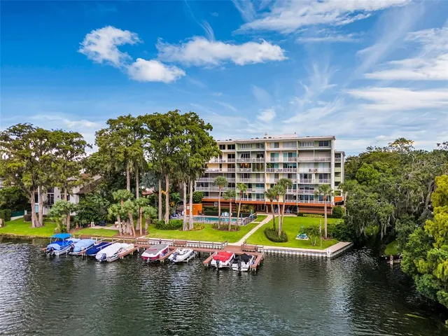 a view of pool with lawn chairs and large trees