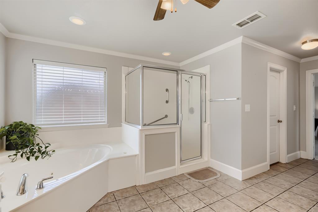603 Ash Street Pilot Point, TX 76258 - Photo 22 of 28 Bathroom featuring a built-in corner soaking tub with deck-mounted fixtures, a glass-enclosed shower, and neutral tile flooring