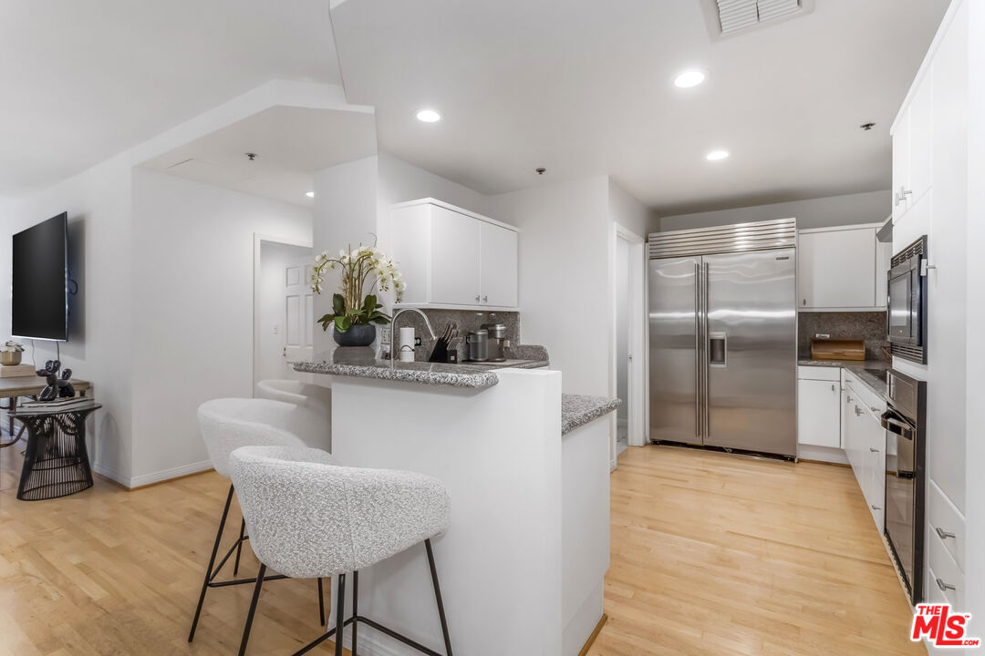 10724 Wilshire Boulevard, Unit 1005 Los Angeles, CA 90024 - Photo 14 of 45 a kitchen with stainless steel appliances kitchen island granite countertop a refrigerator and a sink