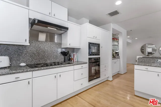 a kitchen with granite countertop a sink stainless steel appliances and white cabinets