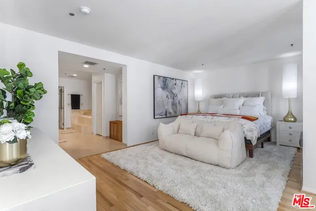 a spacious bedroom with a bed and a potted plant