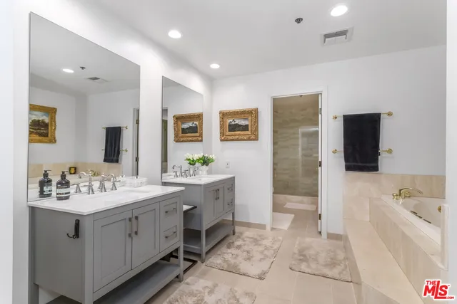 a spacious bathroom with a sink double vanity granite tub shower and a mirror