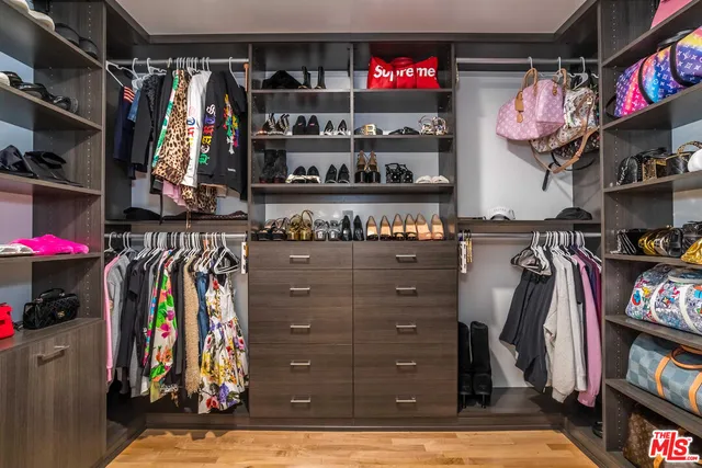a view of walk in closet with clothes and shoes