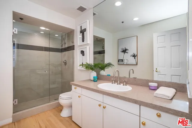 a bathroom with a granite countertop sink a toilet a mirror and shower