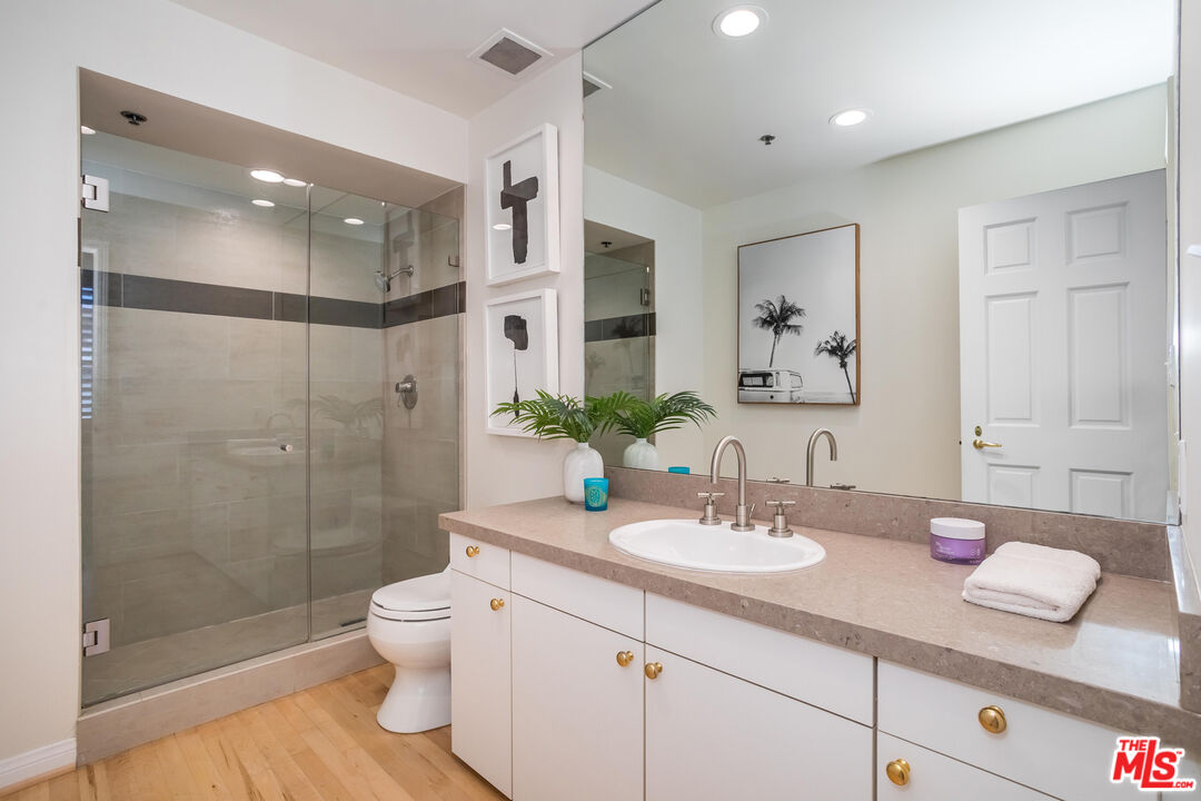 10724 Wilshire Boulevard, Unit 1005 Los Angeles, CA 90024 - Photo 33 of 45 a bathroom with a granite countertop sink a toilet a mirror and shower