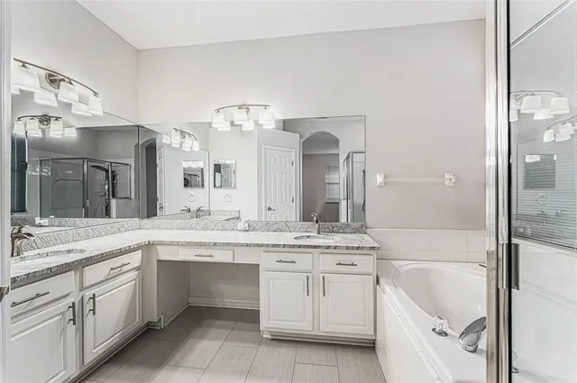a spacious bathroom with a granite countertop sink mirror and bathtub