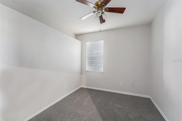 an empty room with a window and a fan