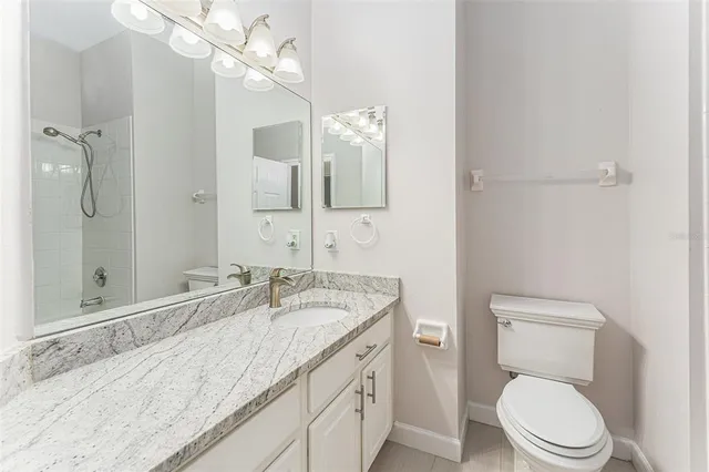 a bathroom with a granite countertop sink a toilet and a mirror