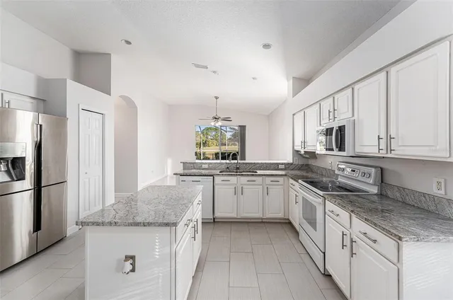 a kitchen with granite countertop a sink stove and refrigerator