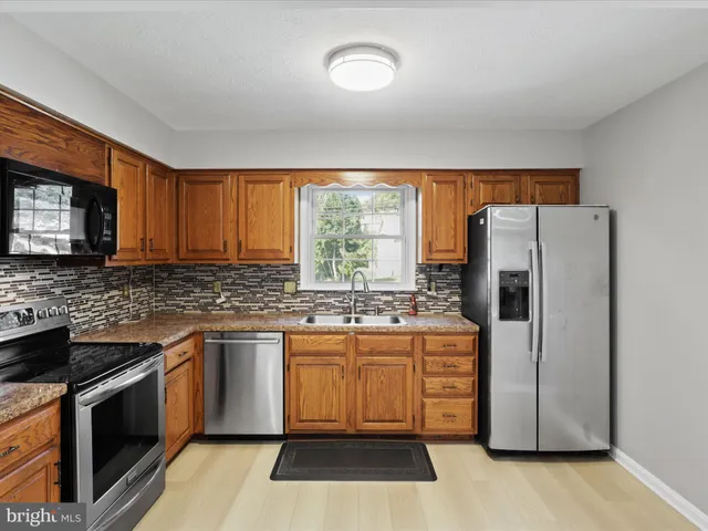 a kitchen with stainless steel appliances granite countertop a stove a refrigerator and a stove top oven