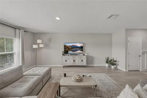 a kitchen with stainless steel appliances granite countertop a stove a refrigerator a sink dishwasher and white cabinets with wooden floor