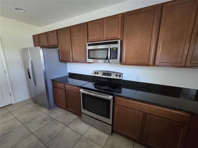 a kitchen with granite countertop wooden cabinets and stainless steel appliances