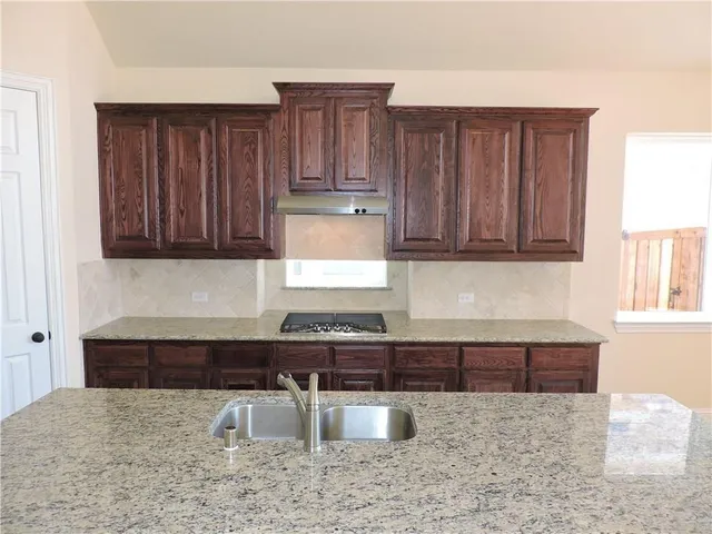 a kitchen with stainless steel appliances kitchen island granite countertop a stove a sink and a refrigerator