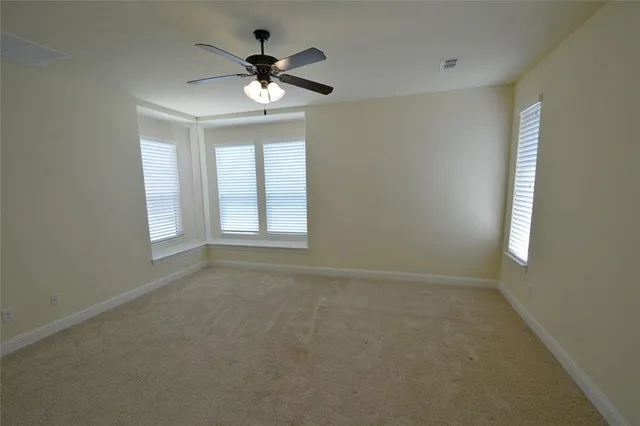 an empty room with windows and ceiling fan