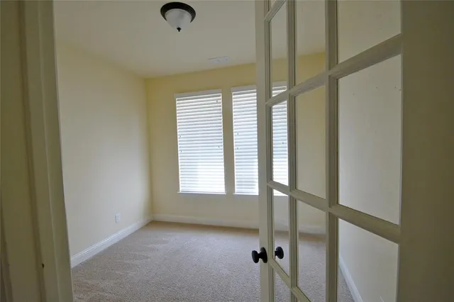 an empty room with chandelier fan and windows