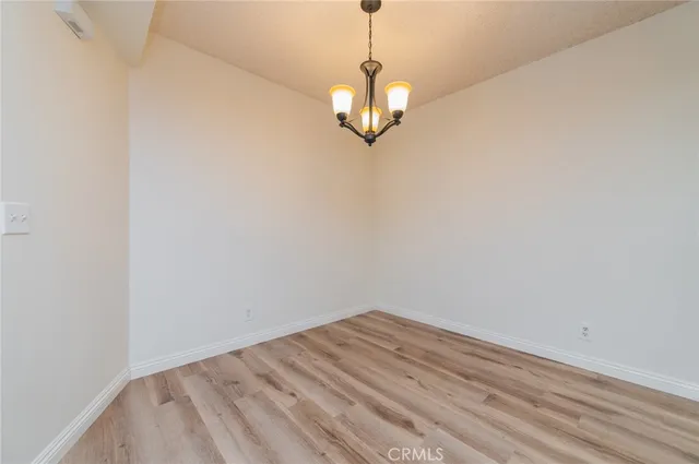 a view of a room with a hanging light and hardwood