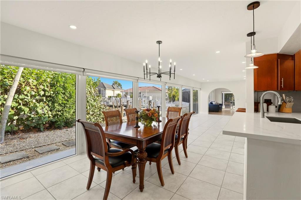 339 Landmark Street Marco Island, FL 34145 - Photo 17 of 50 Dining space with light tile patterned floors, recessed lighting, arched walkways, and a chandelier