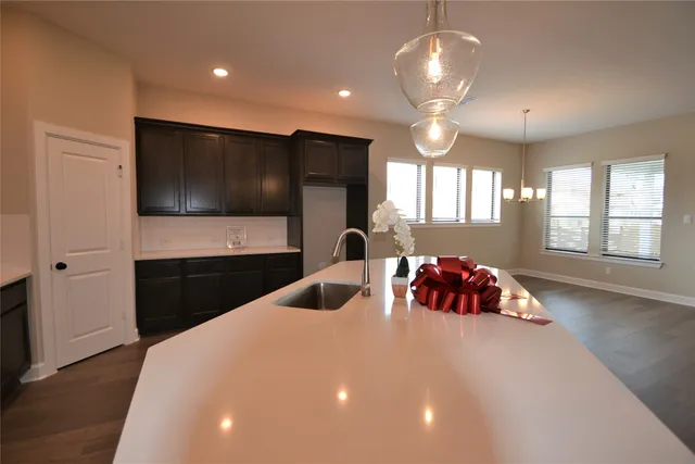 a view of a kitchen with kitchen island stainless steel appliances a stove a sink and a wooden floor