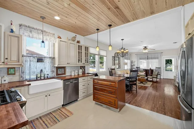 a kitchen with stainless steel appliances a stove a sink dishwasher a oven and white cabinets with wooden floor