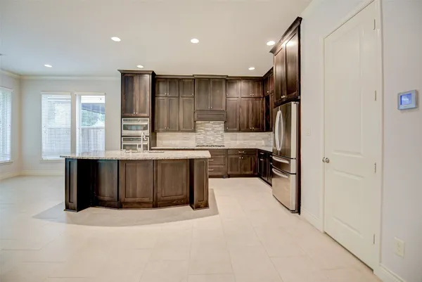 a kitchen with stainless steel appliances kitchen island granite countertop a refrigerator and a sink