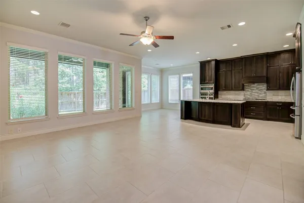 a view of an empty room with kitchen view and a window
