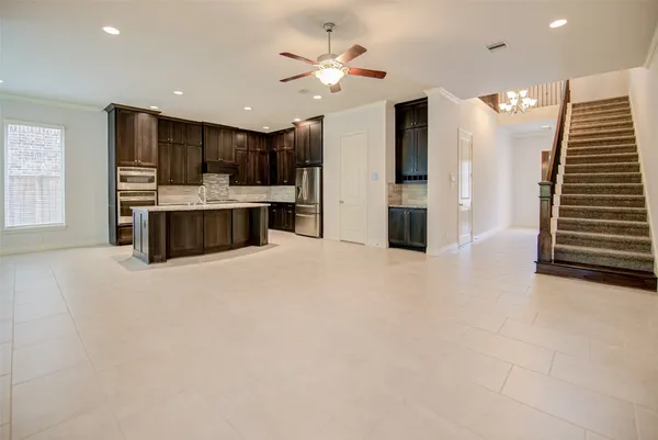 a large white kitchen with a large window a sink and stainless steel appliances