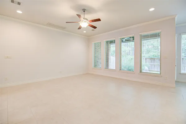 an empty room with windows and ceiling fan